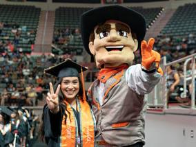 赌博平台 mascot graduate poses beside graduate