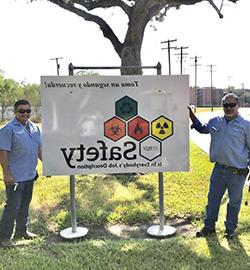 赌博平台 employees next to a 赌博平台 EHSRM banner outside.